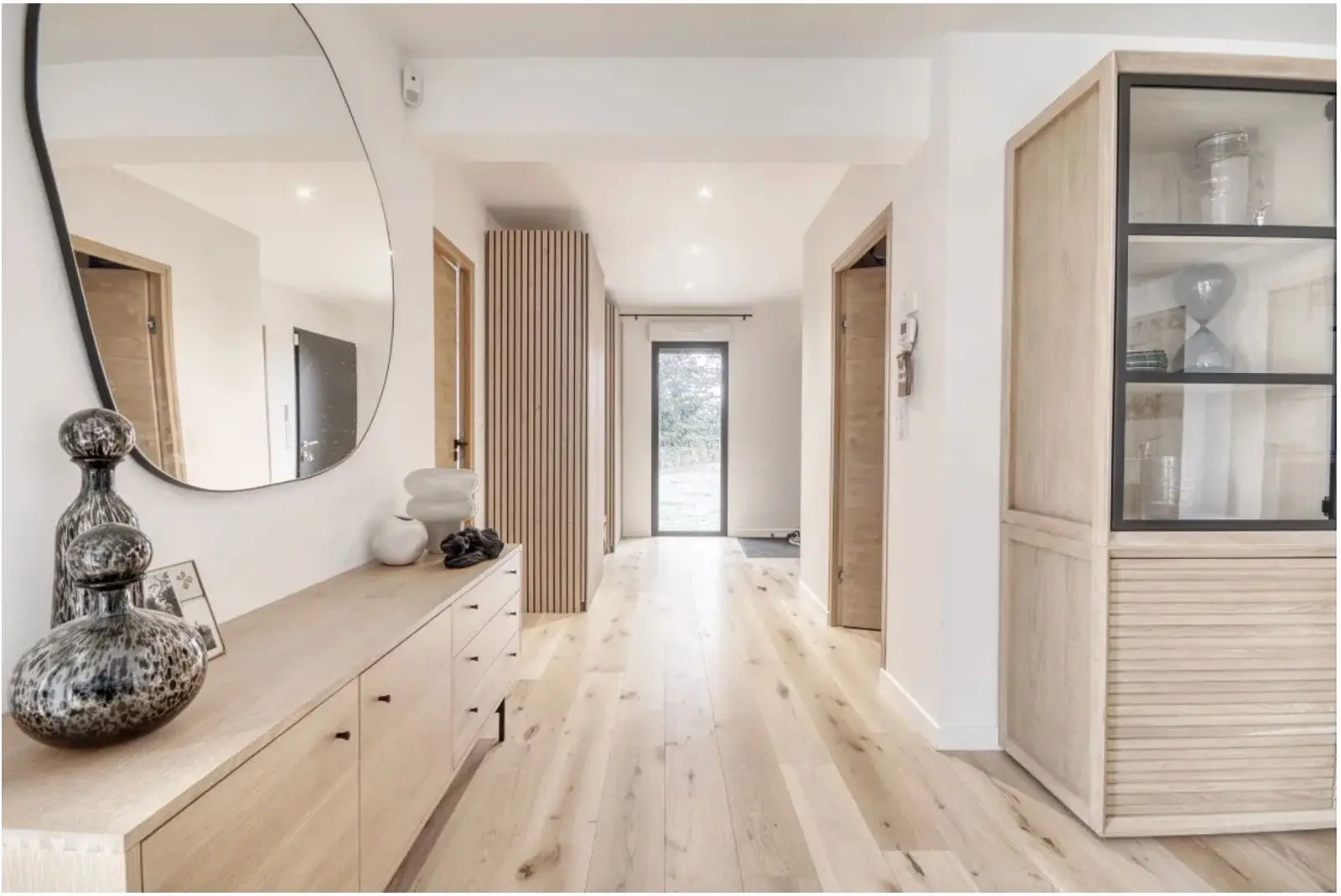 L'entrée rénovée : miroir rond, chêne clair et lumière naturelle